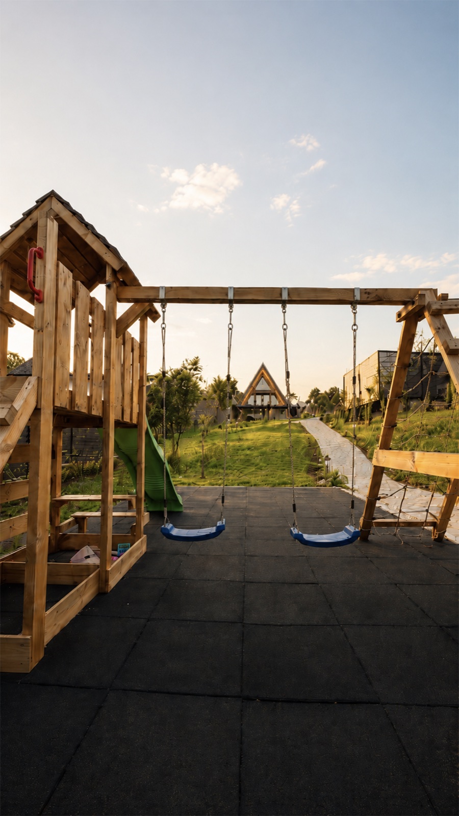 Loc de joacă cu leagăne și cabana A-frame în fundal